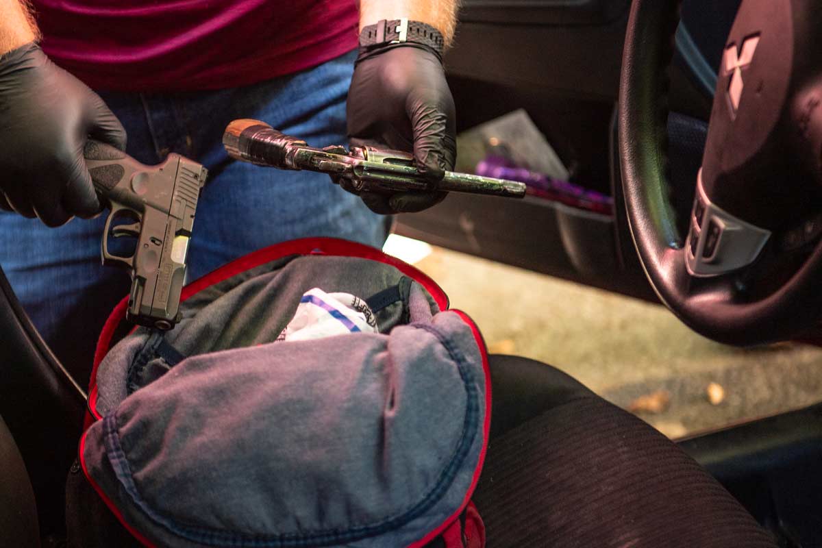 3cgunsfromcar gloved hands take guns out of a bag in a car
