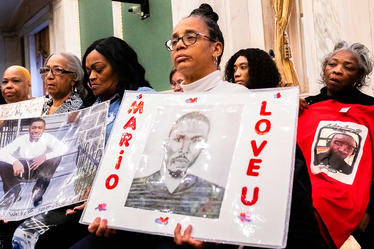 philly-victims-family woman holds up a sign commemorating her dead loved one
